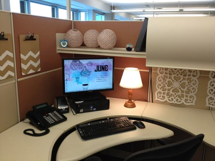 an office cubicle with a computer, phone and other items on the desk in front of it