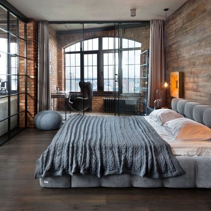 a bedroom with a large bed and lots of windows in the wall next to it