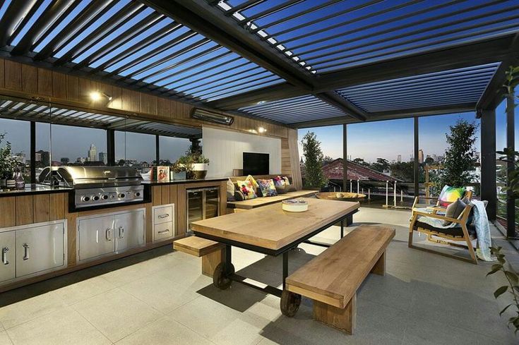 an outdoor kitchen and dining area with large windows