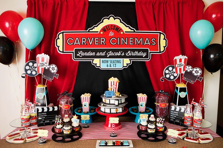 an image of a movie party with popcorn and cakes on the table in front of red curtains