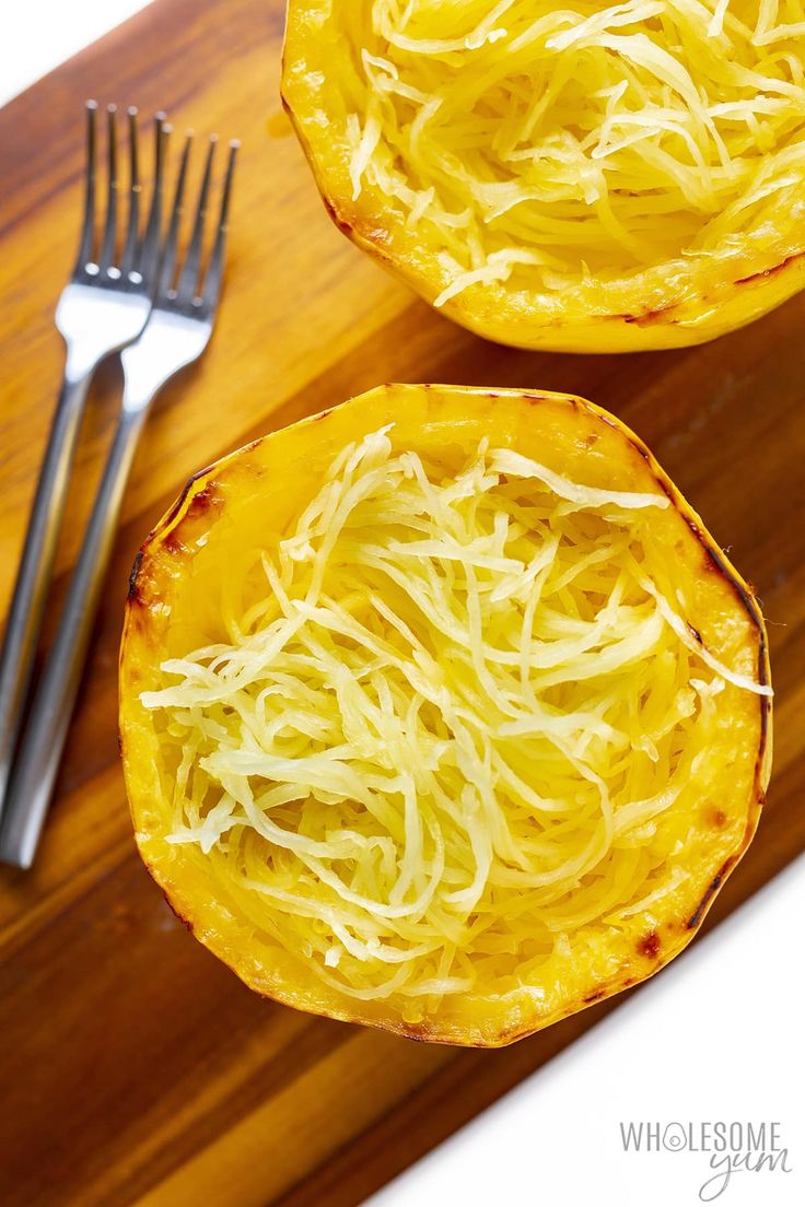 two spaghetti dishes on a cutting board with a fork