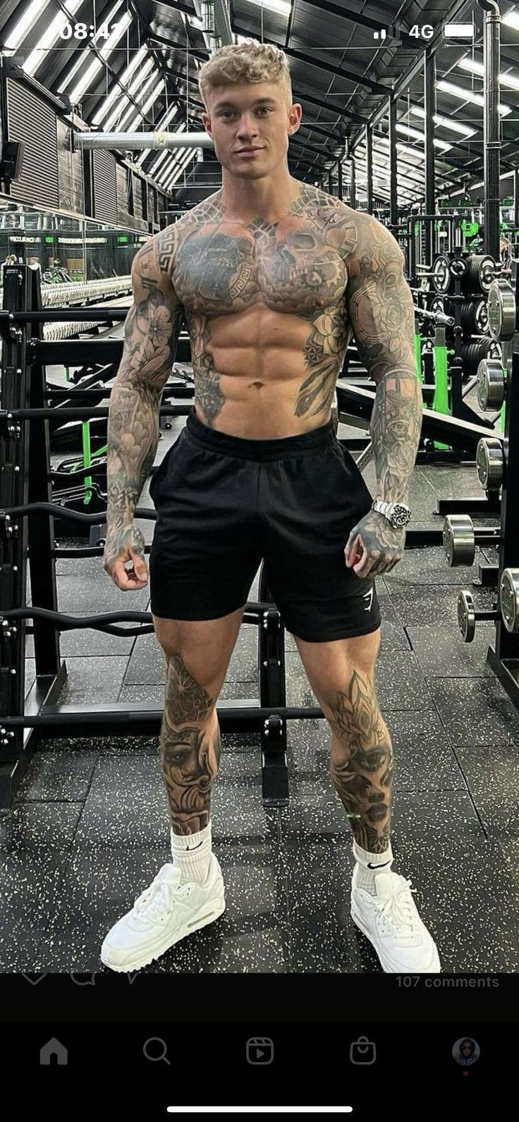 a man with tattoos standing in a gym