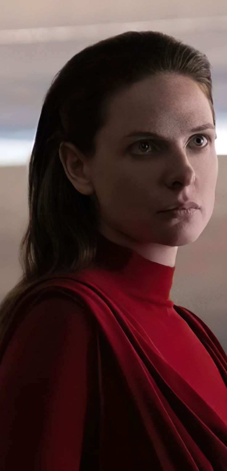 a woman in a red dress looking at the camera with an intense look on her face