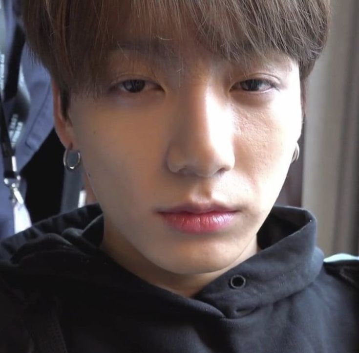 a close up of a person with ear rings on his head and wearing a black hoodie