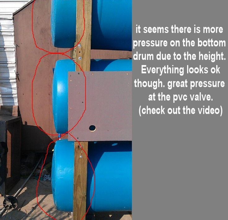 there is a blue barrel attached to the side of a wooden structure with wires running through it