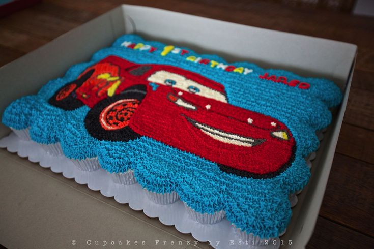 a birthday cake in the shape of a car is on top of a cardboard box