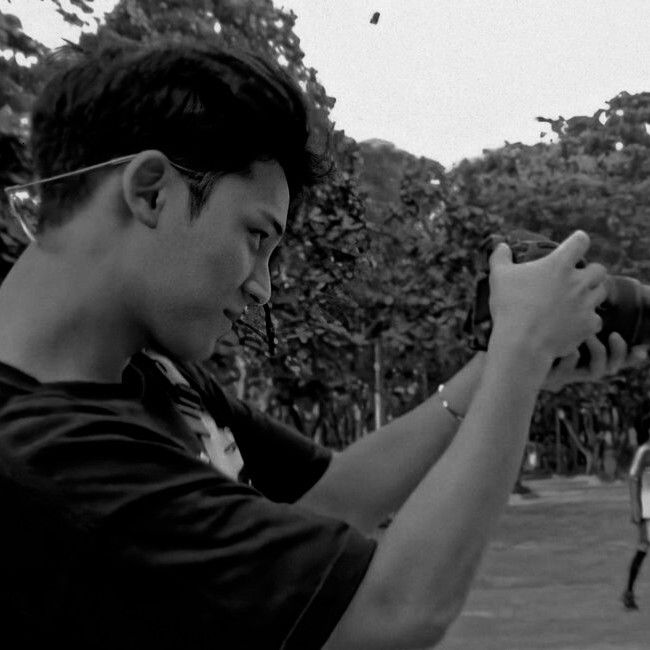 a man holding a camera up to take a picture with another person in the background