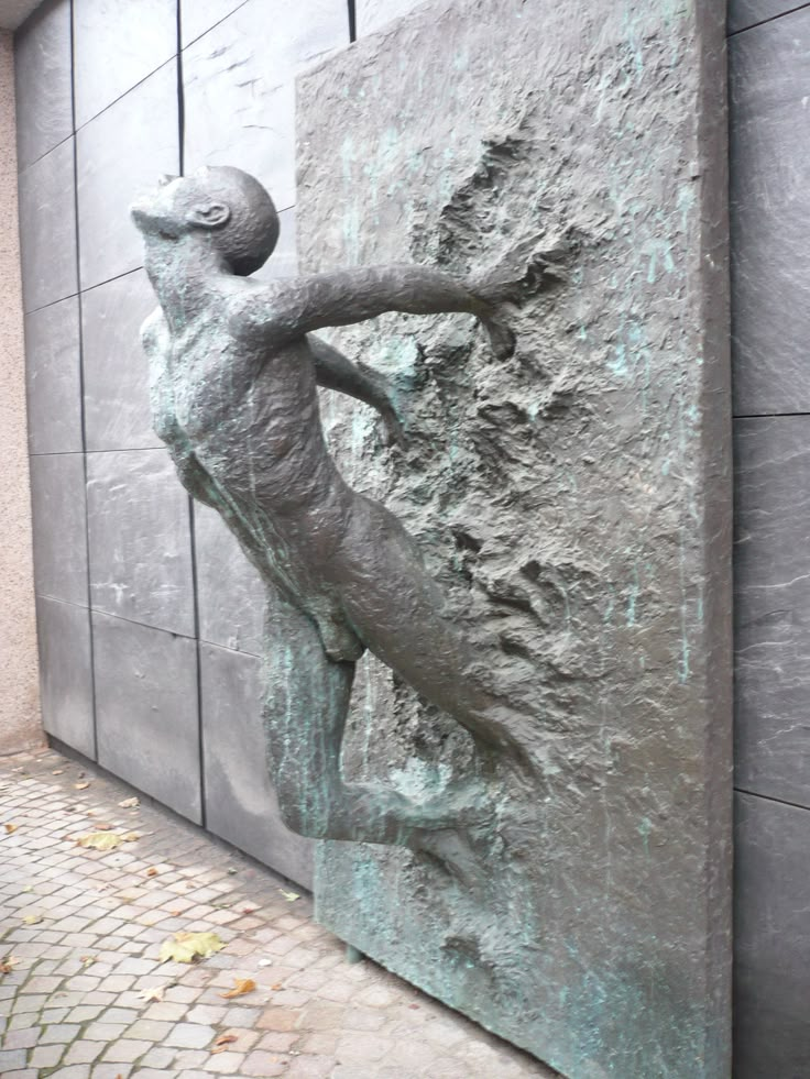 there is a statue on the side of a building that looks like a man climbing