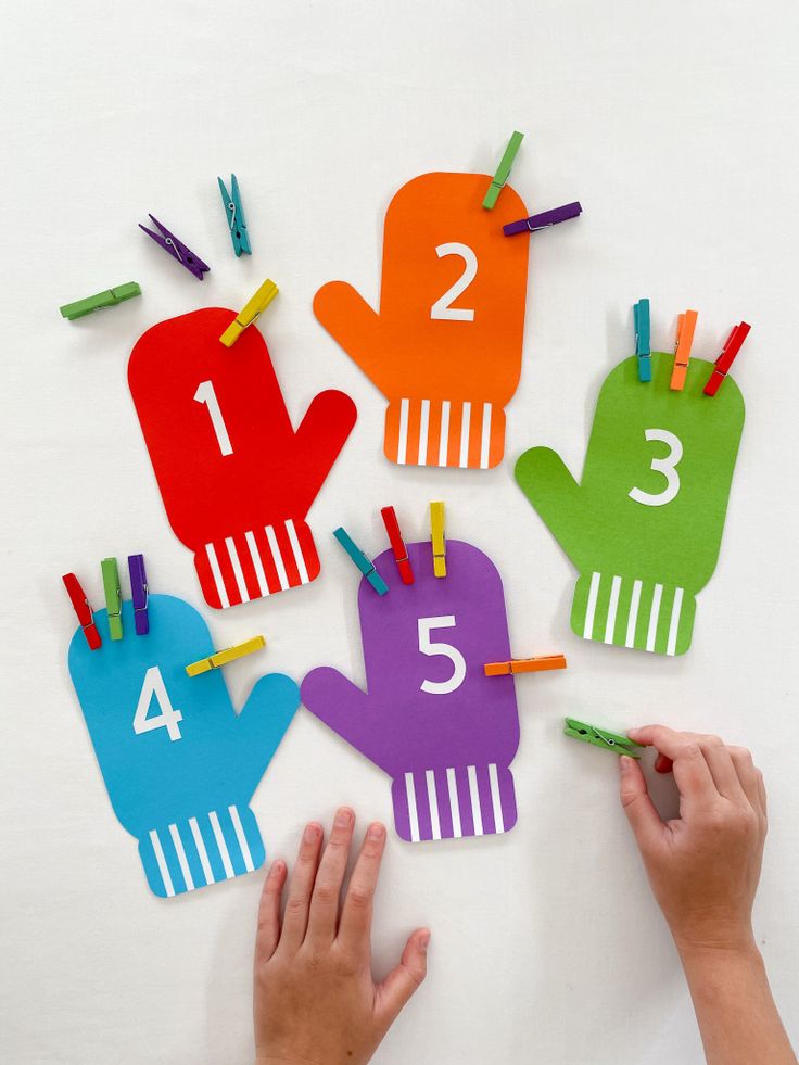 children's hands holding up colorful paper cutouts with numbers and fingers on them