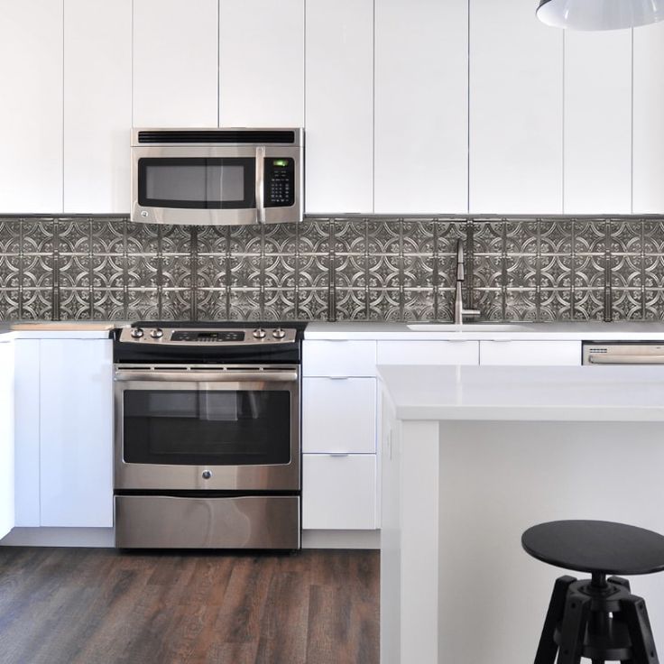 a kitchen with white cabinets and stainless steel stove top oven next to a bar stool