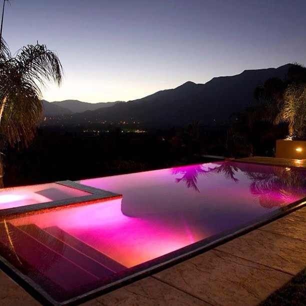 an outdoor swimming pool at night with mountains in the background