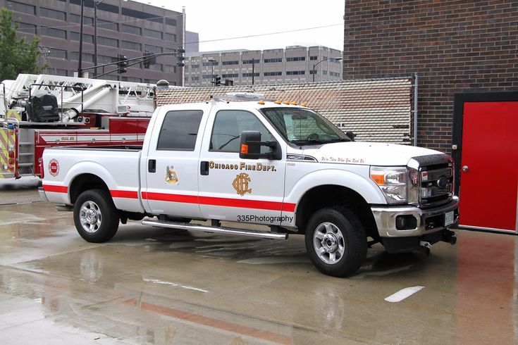 a white fire truck parked in front of a brick building next to a red fire hydrant