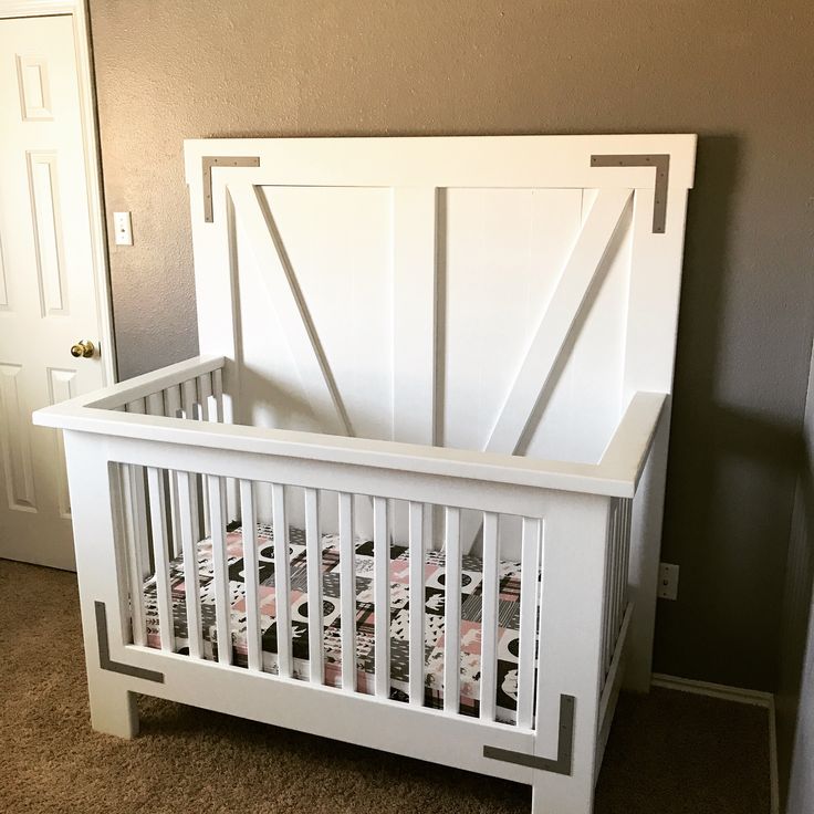 a white crib in the corner of a room with a door on one side