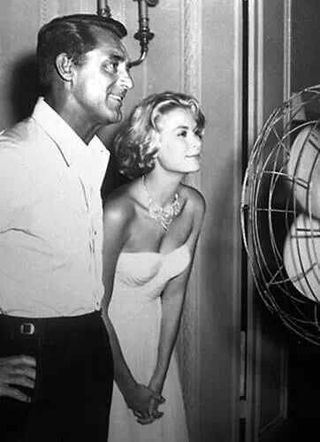 a man standing next to a woman in front of a fan