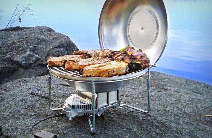 there is a grill on the rocks by the water