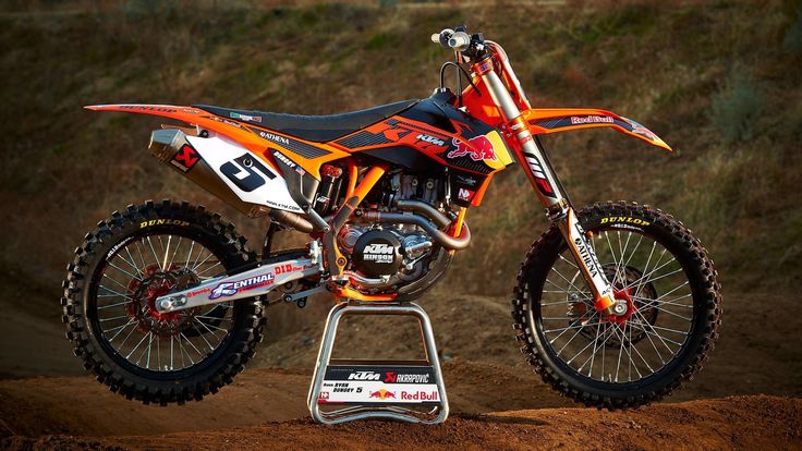 an orange and black dirt bike parked on top of a hill