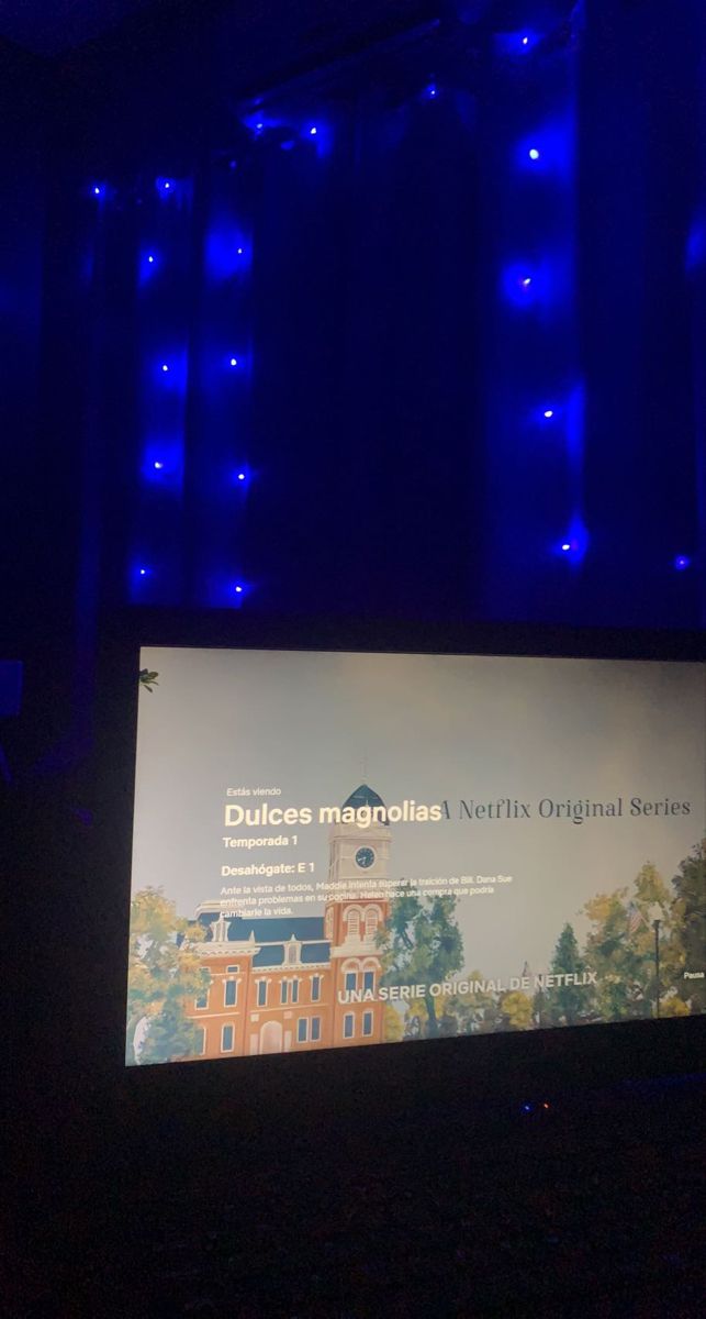 a man standing in front of a projection screen at a podium with an audience watching