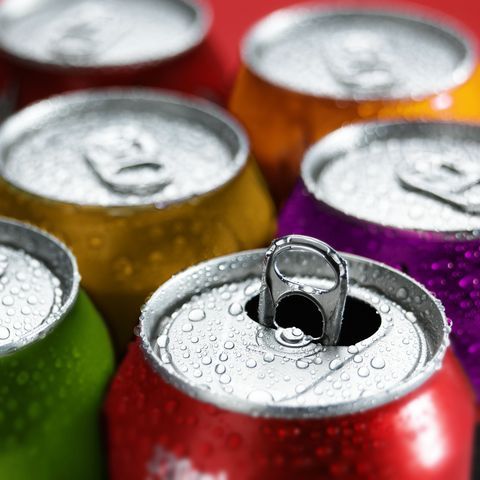 several cans of soda with water droplets on the top one is red, green, yellow, and purple