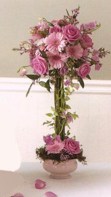 a vase filled with pink flowers sitting on top of a white table next to a wall