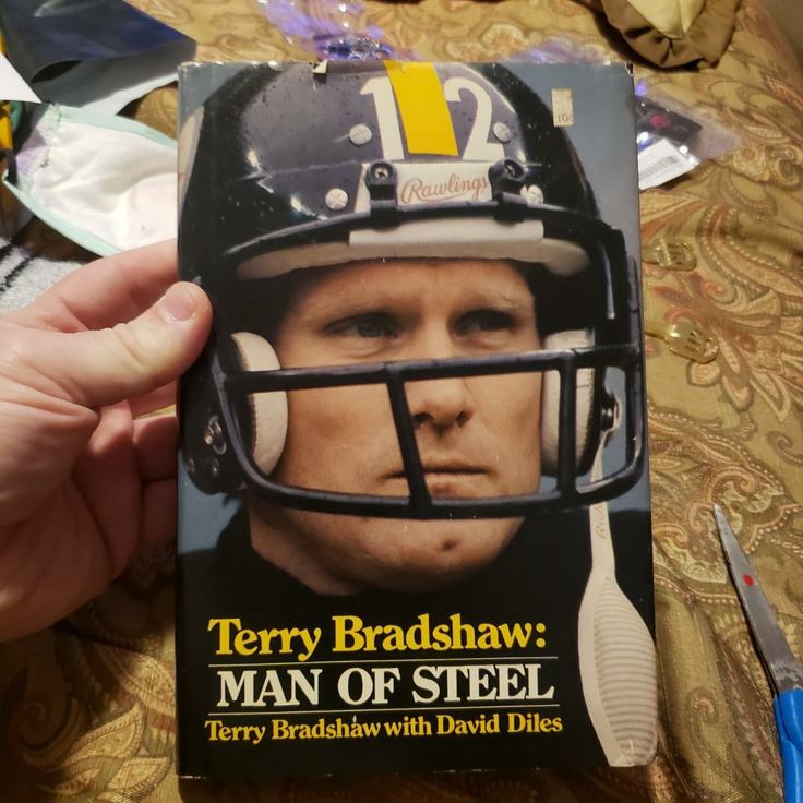 a person holding up a book with a football helmet on it