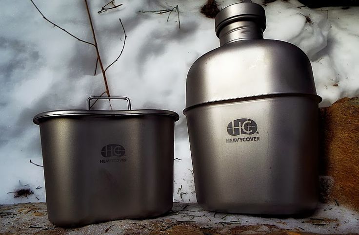 two stainless steel containers sitting next to each other on snow covered ground with plants in the background