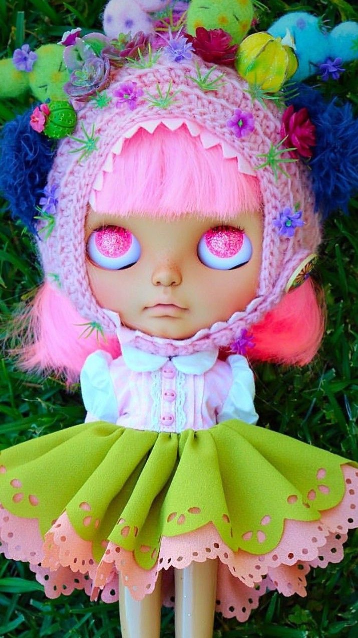 a doll with pink hair and blue eyes wearing a green dress, hat and boots