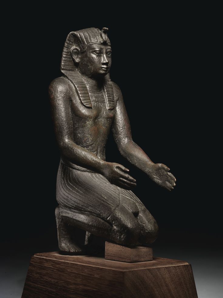 an ancient statue sitting on top of a wooden stand