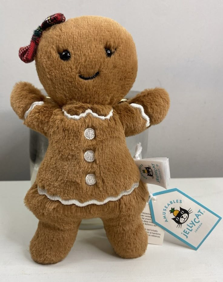 a brown teddy bear with a red bow on it's head and hands in the air