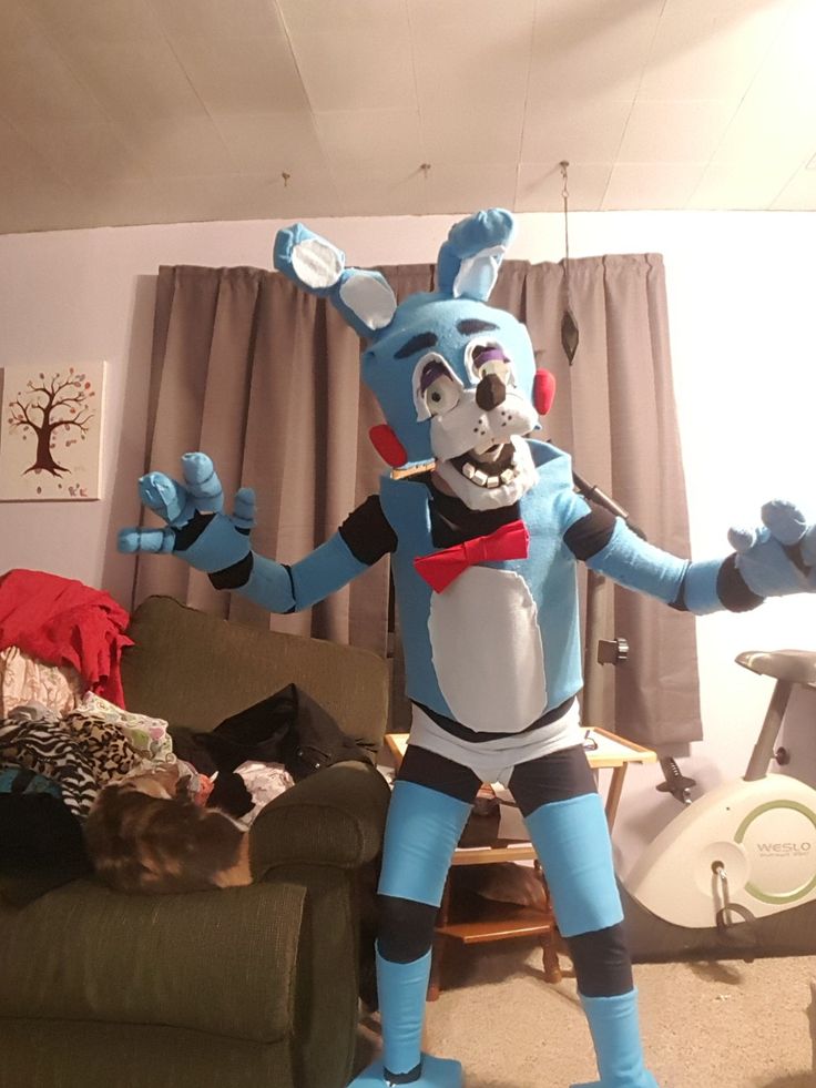 an inflatable blue bunny is standing in the living room with his arms outstretched