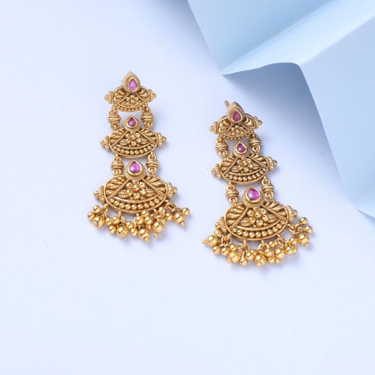 Description Inspired by the shimmering Indian gold jewelry. This Collection is designed to highlight the fine Indian craftsmanship. It is crafted in gold-plated 925 silver with intricate textures and tones. Modern designs adorn you with timeless floral patterns. This jewelry is perfect for wedding and festival events. Created by Paksha design experts, the Swara signature drop earrings gather three floral motifs, coming together in a joyful dance. The pearl drops and pink stones add the right bal 22k Gold Wedding Danglers For Diwali, 22k Gold Danglers For Wedding And Diwali, Yellow Gold Earrings For Wedding And Diwali, 22k Gold Bridal Earrings For Anniversary And Festivals, 22k Gold Bridal Earrings For Festivals And Anniversaries, 22k Gold Chandelier Earrings For Weddings And Festivals, 22k Gold Temple Bridal Earrings For Celebration, 22k Gold Temple Jewelry Bridal Earrings For Celebration, 22k Gold Bridal Earrings For Celebration