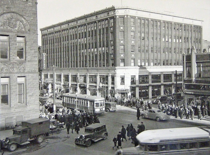 an old black and white photo of people on the street in front of some buildings