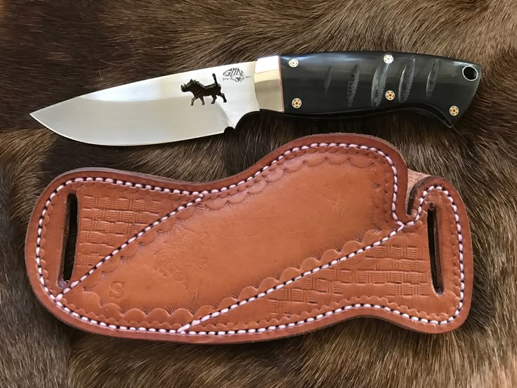 a leather sheath with a knife on top of it next to a black and white blade