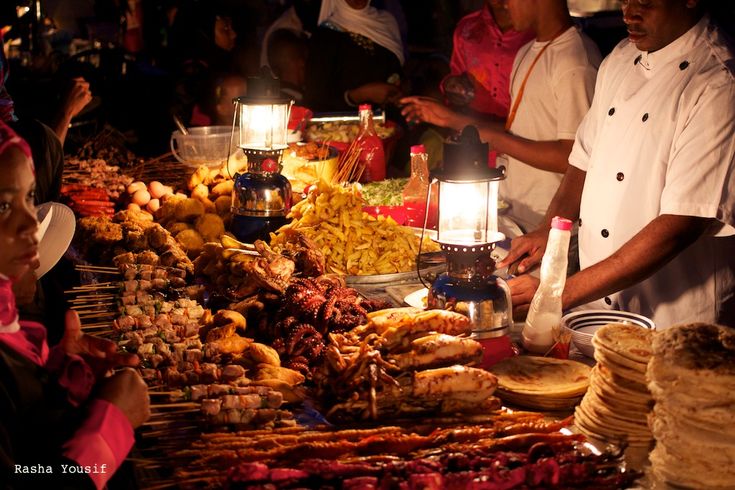 several people standing around a table with food on it and lit candles in front of them