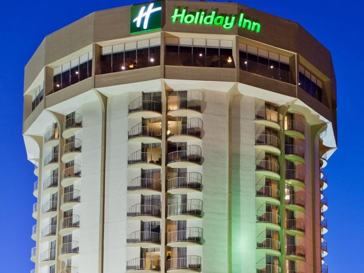 the holiday inn is lit up at night in front of a building with balconies