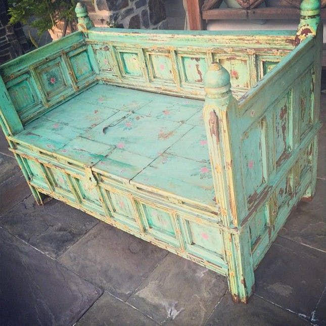 an old green bed frame sitting on top of a stone floor