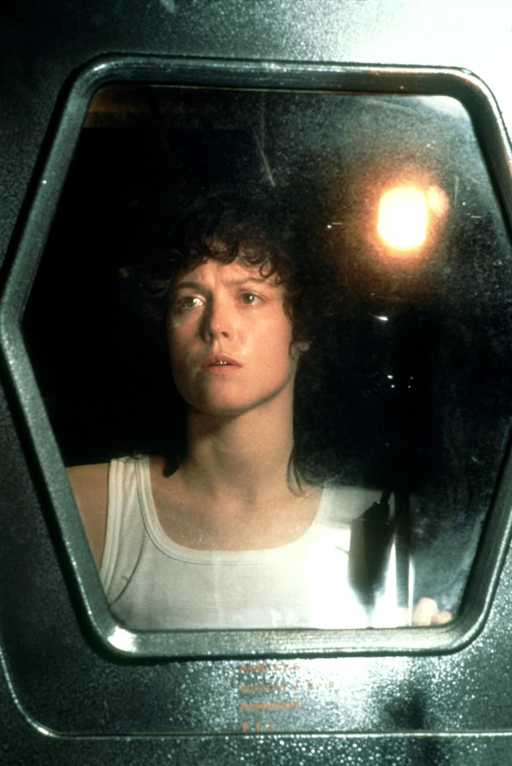 a young man with curly hair is looking out the window at something in the distance