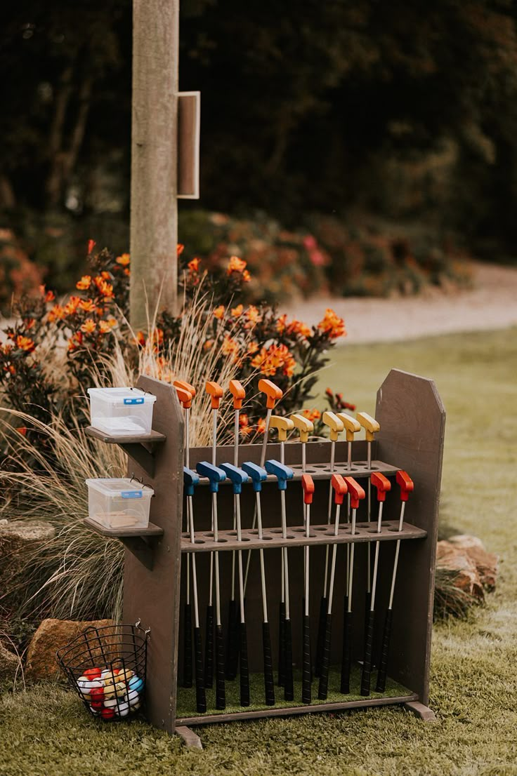 a rack filled with lots of colorful toothbrushes next to a pole and flowers