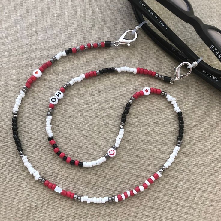 Best selling glasses chain! This Ohio State inspired chain shows off your football pride! It is made with red, black, silver, white and fun beads. Add a FREE PERSONALIZATION to make it yours or an original gift, i.e., Ohio, OH-IO, OSU, Buckeyes, etc. If no personalization is specified, no letters will be used. The photo is personalized. Securely holds your sunglasses, readers, or mask in style or connect the ends to wear as a necklace. See shop for many other color patterns to choose from. Beading and patterns vary as no 2 chains are alike! Message for specific customization - fees will apply.  Size: 27"  Made in Las Vegas. Visit our other store: MADELV.com See other Ohio listings or search "Ohio" https://falabco.etsy.com/listing/1031110013 https://falabco.etsy.com/listing/1172536686 https Customized Red Casual Jewelry, Customized Casual Red Jewelry, Casual Customized Red Jewelry, Casual Red Customized Jewelry, Eyeglasses Chain, Osu Buckeyes, Black Beaded Jewelry, Personalized Football, Eyeglass Chain