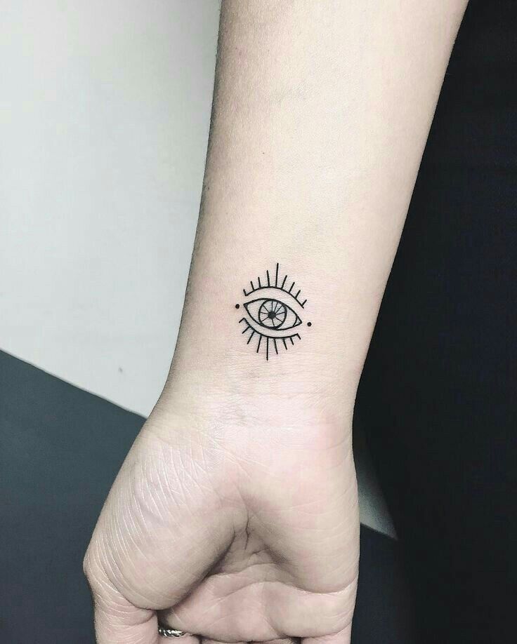 a small tattoo on the wrist of a woman's left hand with an all seeing eye