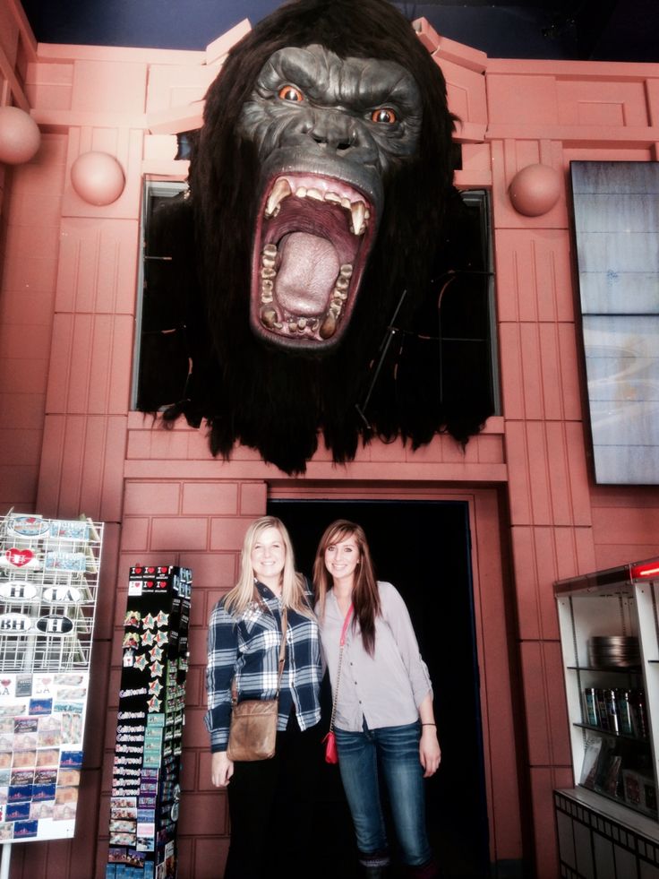 two women standing in front of a giant gorilla head