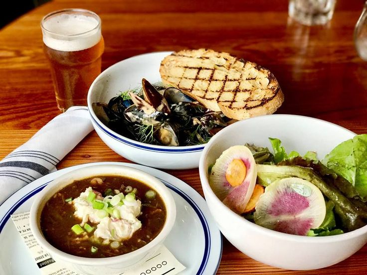 three bowls of food are sitting on a table next to a glass of beer and a sandwich