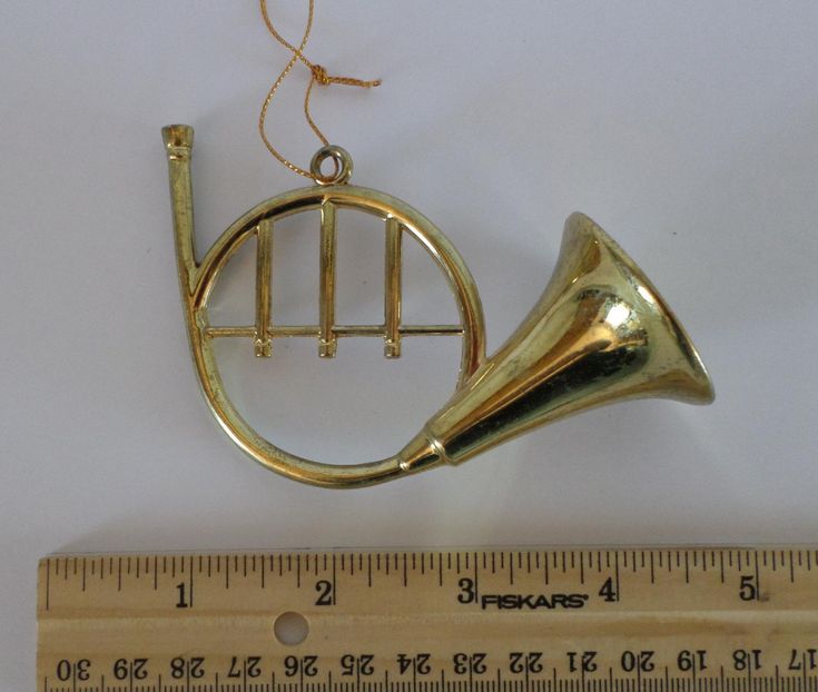 a brass musical instrument ornament hanging from a ruler