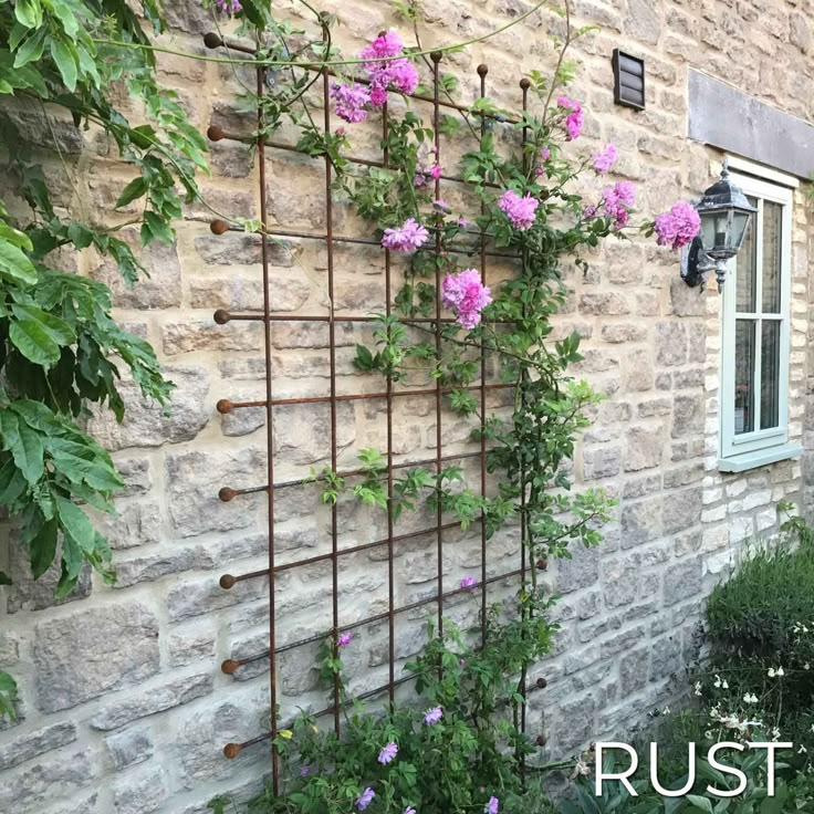 an old brick building with pink flowers growing on it's side and the words rust in front