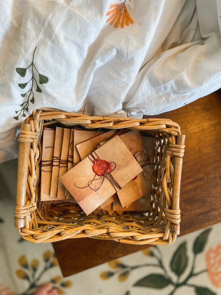 a wicker basket filled with brown cards on top of a wooden table next to a white sheet