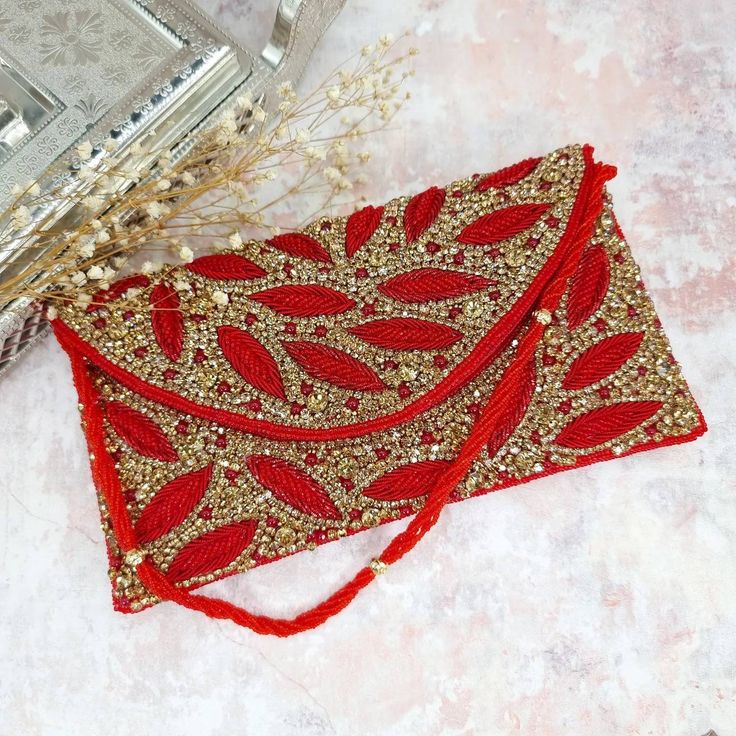 Featuring a Red Antique Gold Clutch bag in cotton base with a flap opening with a cut dana beaded strap, Handcrafted with Intricate Stone, beaded crystal, Cut dana and rhinestones.  Bag Measuring 26cm in length and 13cm in width. When your outfit could use a final, eye-catching addition, make sure the Fancy Fab's 'Zaina' Red Antique Gold Clutch is on-hand!  Perfect for evening parties and a special occasion.  This item made of is 100% handwork We try to take pictures as normal as we can but colo Cut Dana Work Embroidery, Orange Clutch, Gold Clutch Bag, Bridal Clutch Bag, Zardosi Work, Beaded Strap, Embellished Clutch, Couture Embroidery, Gold Clutch