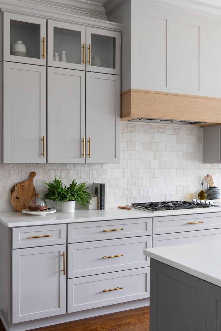 a kitchen with white cabinets and gold handles on the countertops, along with a wooden cutting board