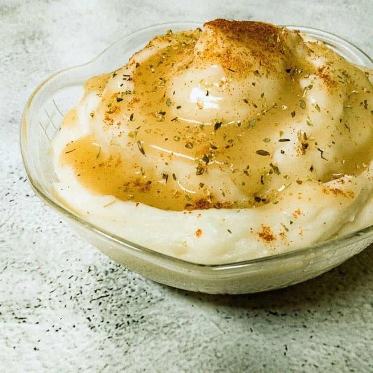 a bowl filled with mashed potatoes covered in gravy and topped with seasoning