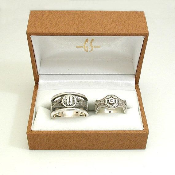 two silver rings in a box on a white surface with a monogrammed logo