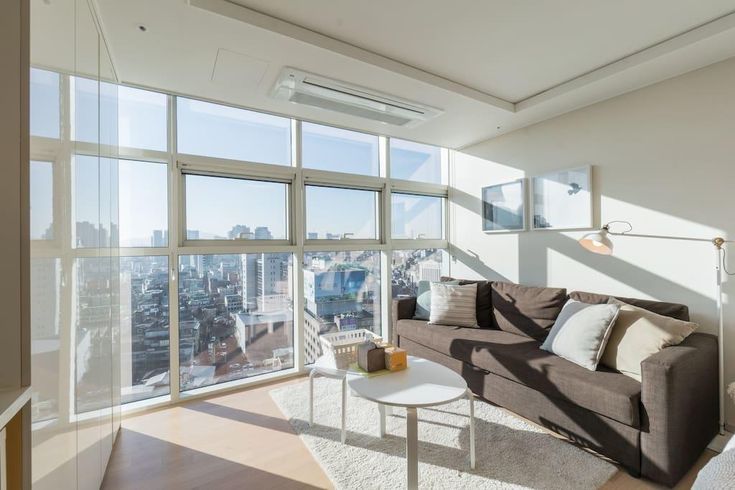 a living room filled with furniture and large windows overlooking the cityscape in the distance