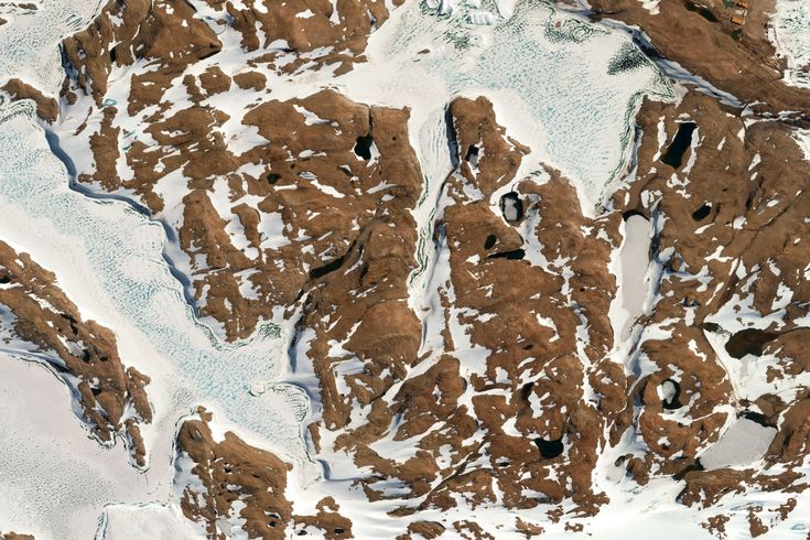 an aerial view of snow covered mountains and valleys